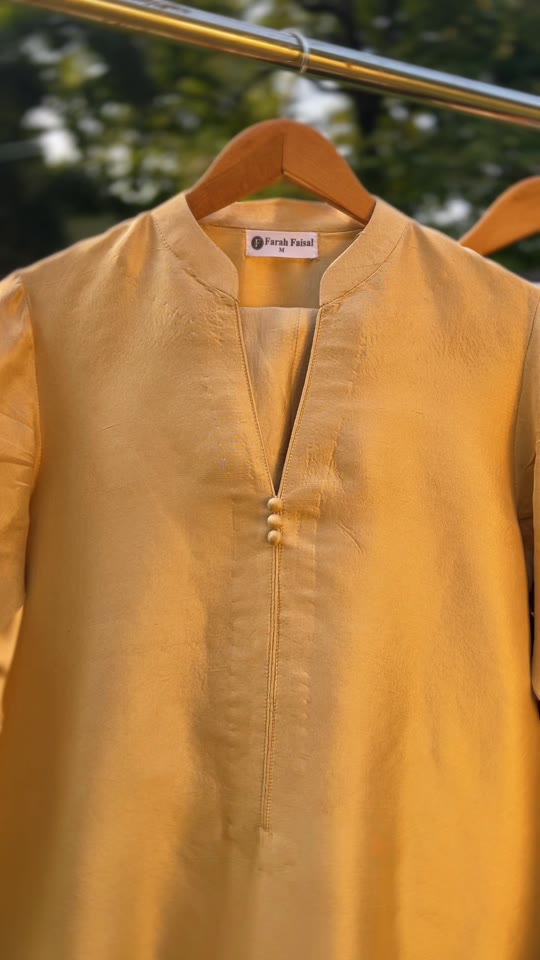 Mustard kurta on a hanger with the Farah Faisal label